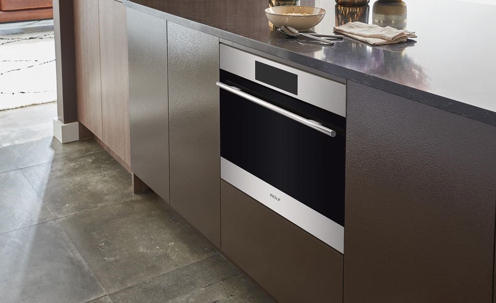 Sub-Zero, Wolf, and Cove's 24" E Series Transitional Speed Oven - SPO24TE/S/TH inside a cabinet with brown panels