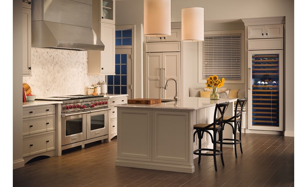 La hotte murale Wolf 60 po Pro- profondeur 24 po (PW602418) est d’une beauté indémodable dans cette cuisine élégante d'inspiration française, avec ses armoires blanches et son comptoir en marbre