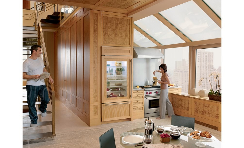 Hotte murale Wolf 30 po à profil bas (PW302210) dans un design de cuisine personnalisé avec de hauts plafonds, de grandes fenêtres et des armoires en bois naturel