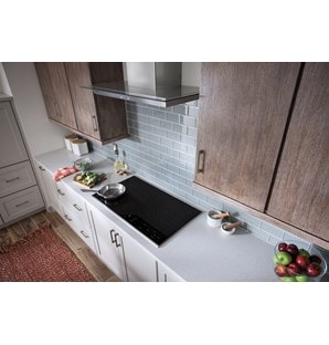 La hotte murale Wolf 36 po pour surface de cuisson - verre (VW36G) est présentée dans un design de cuisine confortable avec des armoires en bois aux tons chauds et un dosseret en carrelage