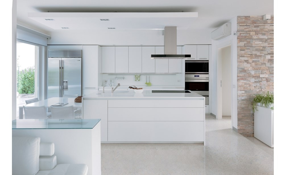 La hotte pour îlot à surface de cuisson Wolf de 42 po - noire (VI42B) se fond harmonieusement dans un design de cuisine linéaire blanc avec des armoires sans poignées