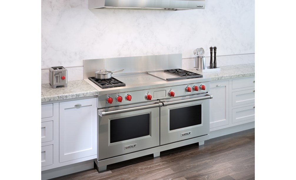 The Wolf 60" Dual Fuel Range 4 Burner Infrared Griddle French Top (DF604GF) shown with granite counter tops and country kitchen cabinets.