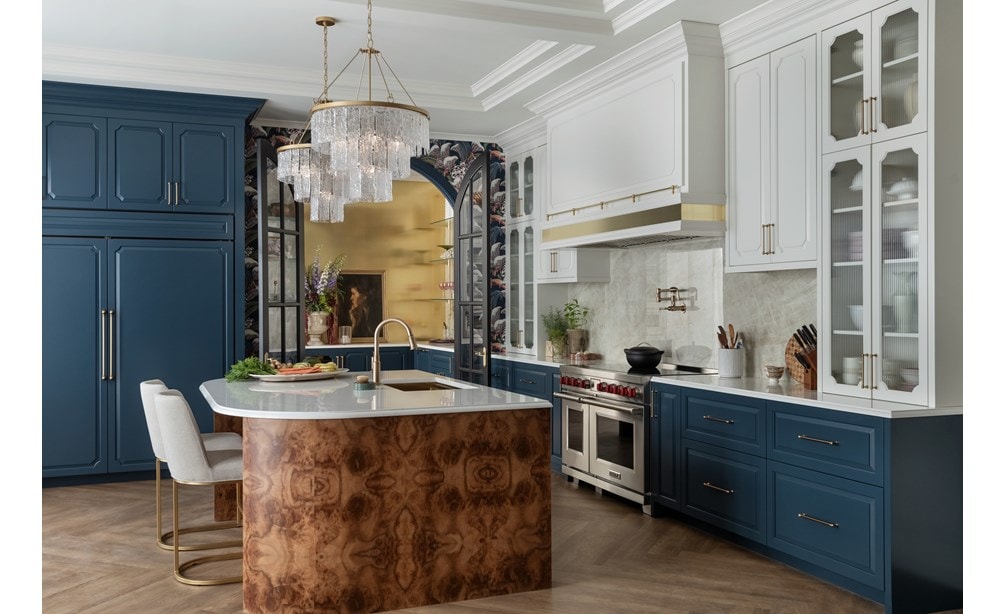 Wolf Professional Induction Range with stainless accent oven door and iconic red knobs displayed in an open kitchen design featuring Sub-Zero Classic Refrigerator and Freezer hidden within custom blue cabinetry .